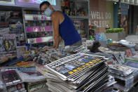 A vendor adjusts copies of Apple Daily at a news stand at a downtown street in Hong Kong Friday, June 18, 2021. The pro-democracy paper increased its print run to 500,000 copies on Friday, a day after police arrested five top editors and executives and froze $2.3 million in assets linked to the media company. (AP Photo/Vincent Yu)