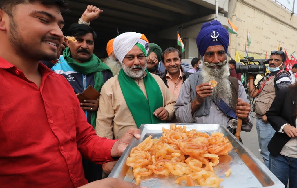 Indian farmers celebrate at the Delhi-Uttar Pradesh border after the announcement of the repeal of the farm laws (EPA)