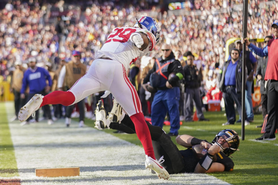 Washington Commanders quarterback Sam Howell (14) is knocked out of bounds by New York Giants safety Xavier McKinney (29) after scoring a touchdown during the first half of an NFL football game, Sunday, Nov. 19, 2023, in Landover, Md. (AP Photo/Andrew Harnik)