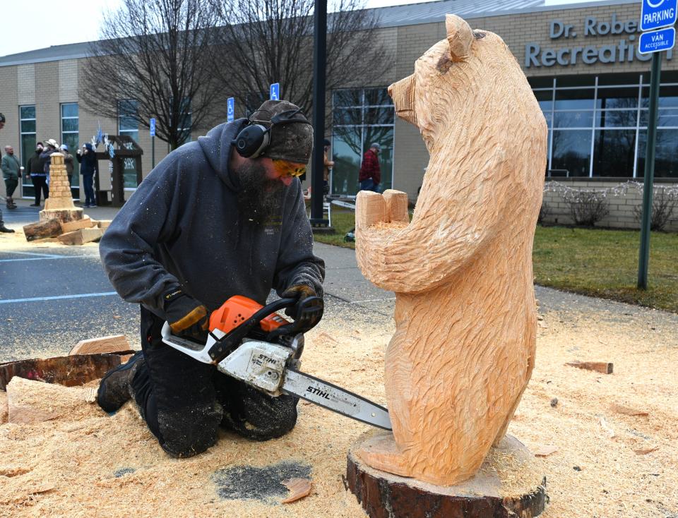 Scott Lepley uses his chainsaw to add details to finish the carving.