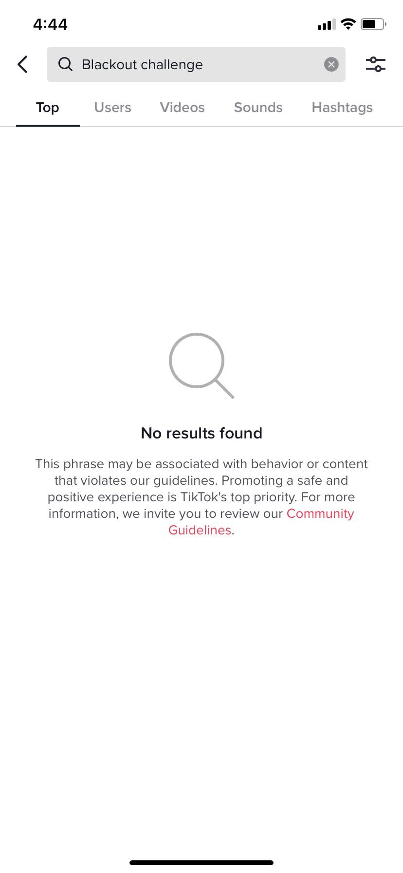 TikTok's user interface, the text "Blackout challenge" is typed into the search bar. The screen shows no results and a statement that the phrase may be associated with behavior or content that violates tiktok's community guidelines.