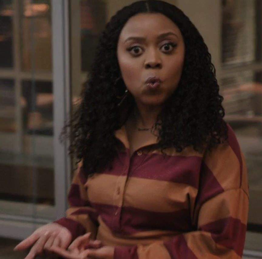 Woman with surprised expression sitting indoors, wearing a striped shirt