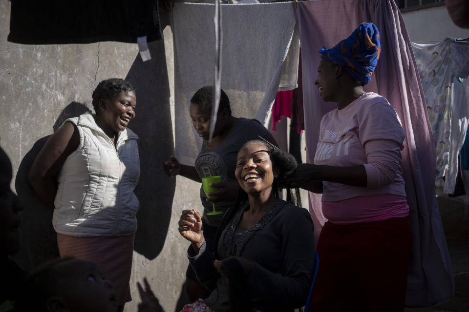Fellowship Mukanhairi, the daughter of a blind Zimbabwean migrant, has her hair styled in the courtyard of their building in Johannesburg, South Africa on April 16, 2020. A total of 23 families of blind and disabled foreign nationals living in a dilapidated building and earning a living by street begging have been hard hit by South Africa's lockdown as they are forced to remain indoors. (AP Photo/Bram Janssen)