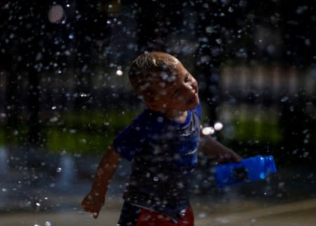 A child cools off in a park water feature in the Shaw neighbourhood during a heat wave in Washington