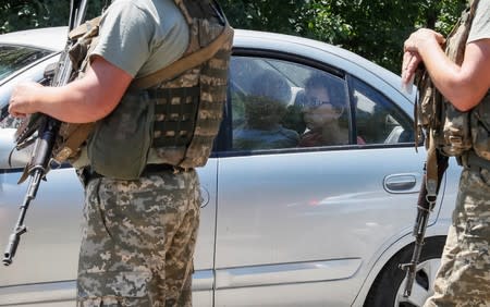 A woman looks out of a car window as she crosses the contact line between pro-Russian rebels and Ukrainian troops as members of the Ukrainian State Border Guard Service stand guard, in Mayorsk