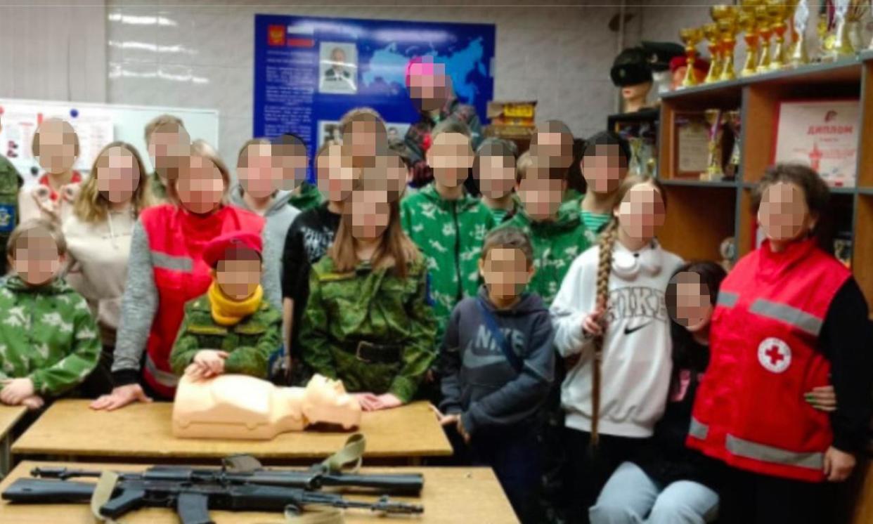 <span>A screenshot of a deleted image showing Russian Red Cross staff posing with Kalashnikov rifles at a military event for children. </span><span>Photograph: Battle Brotherhood</span>