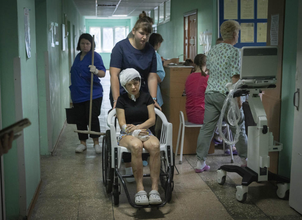 A hospital nurse pushes a wheelchair carrying a woman wounded by the Russian rocket attack at a shopping centre in a city hospital in Kremenchuk in Poltava region, Ukraine, Tuesday, June 28, 2022.(AP Photo/Efrem Lukatsky)