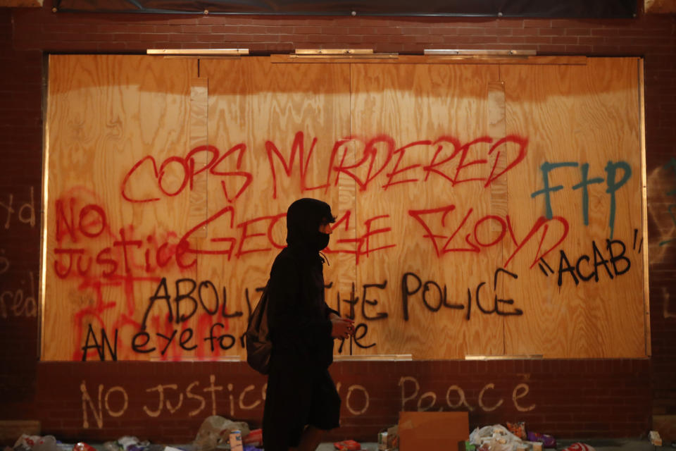 FILE - In this Thursday, May 28, 2020 file photo, a person walks past a building covered with graffiti in Minneapolis, amid protests over the death of George Floyd, a Black man who died in police custody. Former Officer Derek Chauvin’s April 2021 prosecution for the death of Floyd illustrates that officers who come to public attention in abuse cases often had a string of prior allegations of abuse. (AP Photo/John Minchillo, File)