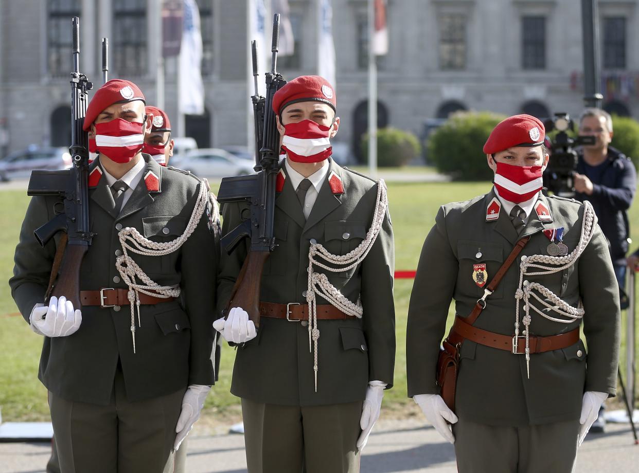 Austrian soldiers wear protective masks showing the Austrian national flag during a military ceremony on the occasion of the 75th anniversary of the re-establishment of the Republic of Austria in Vienna on Monday, April 27, 2020. The Austrian government has moved to restrict freedom of movement for people  in an effort to slow the onset of the COVID-19 coronavirus.