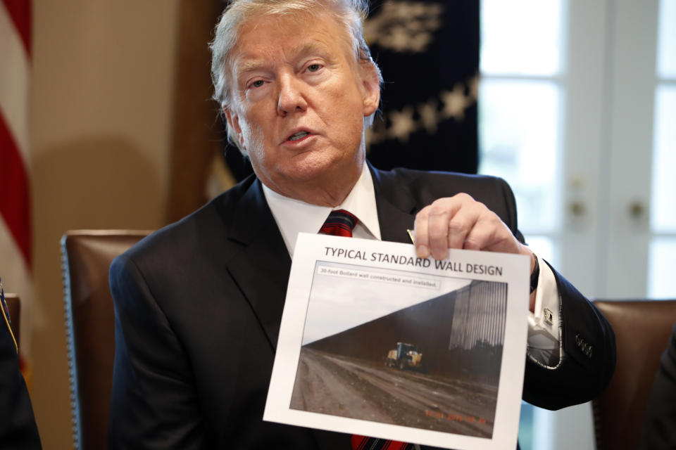 President Donald Trump holds a photo as he leads a roundtable discussion on border security with local leaders, Friday Jan. 11, 2019, in the Cabinet Room of the White House in Washington. (Photo credit: AP Photo/Jacquelyn Martin)