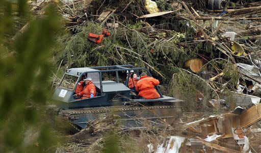 Search workers ride on a tracked vehicle Sunday, March 30, 2014, through the debris field of the massive mudslide that struck the community of Oso, Wash., on Saturday, March 22, 2014, as the search for victims continued near Darrington, Wash. (AP Photo/Ted S. Warren)