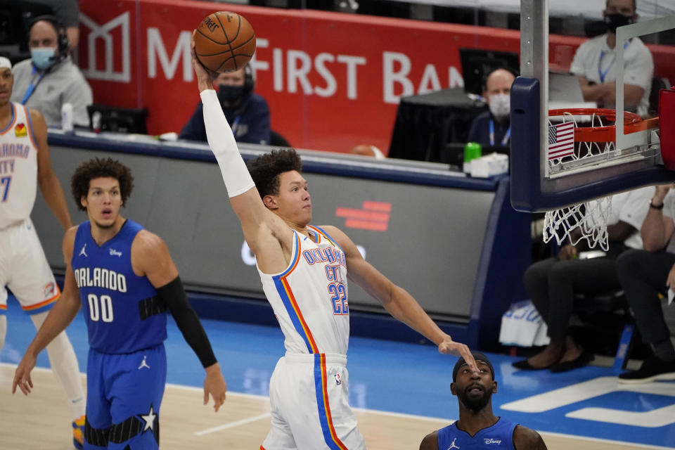 Oklahoma City Thunder forward Isaiah Roby (22) goes up for a dunk between Orlando Magic forward Aaron Gordon (00) and guard Terrence Ross during the second half of an NBA basketball game Tuesday, Dec. 29, 2020, in Oklahoma City. (AP Photo/Sue Ogrocki)