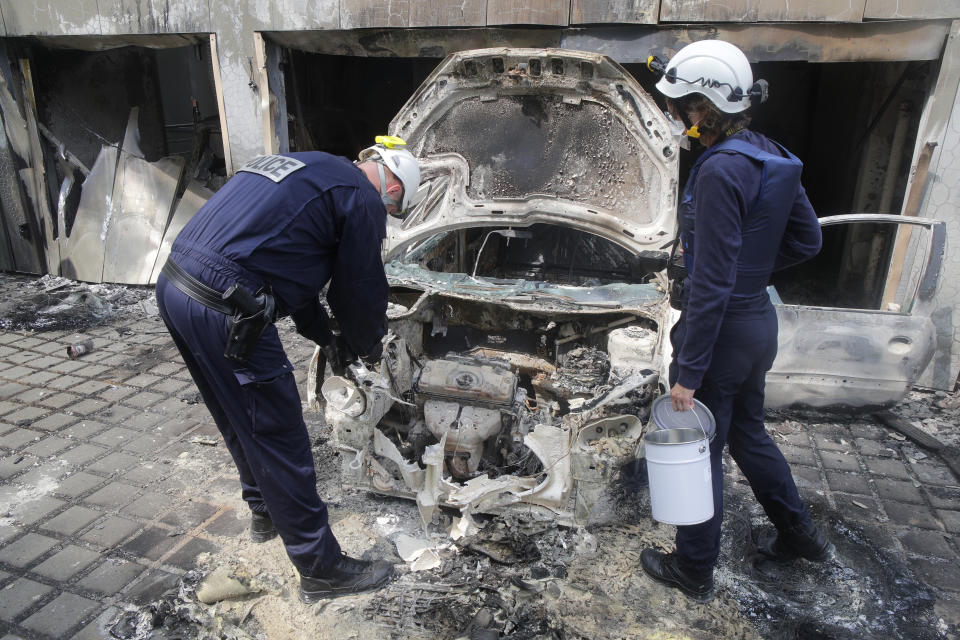 FILE - Police officers work at a charred car at the city hall of Mons-en-Barœul, northern France Thursday, June 29, 2023. Small-town mayors where vehicles were torched, fires lit and police attacked are scratching their heads, trying to figure out why them, why now and whether France's urban blights that previously seemed far away are sinking roots into their peace and quiet, too. (AP Photo/Michel Spingler, File)