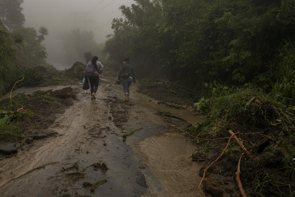 Mujeres caminan por un camino lodoso hacia Comasagua, El Salvador, el lunes 10 de octubre de 2022. Al menos cinco soldados murieron el lunes en las cercanías cuando la pared de una casa se derrumbó mientras se refugiaban de la lluvia. Habían sido desplegados en la zona para combatir a las pandillas. (Foto AP/Moisés Castillo)