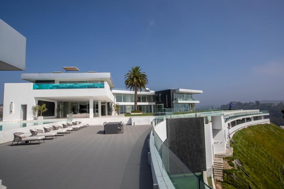 a white building and row of white pool lounge chairs at mansion The One Bel Air