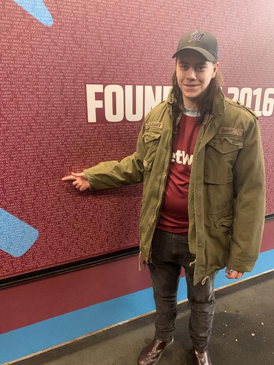 Mark's son, Jack Sullivan, pointing to his own name on the Founder's Poster at West Ham's London Stadium