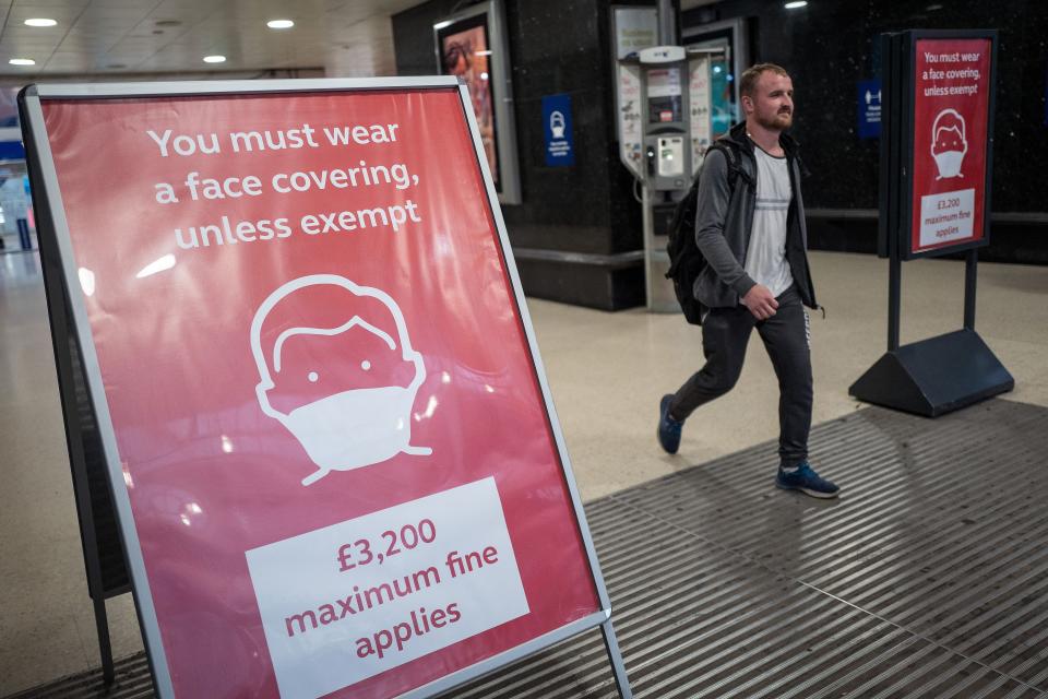 A man, not wearing a face covering, passes signs telling travellers they must wear face mask unless they are exempt, as he leaves Victoria station during the evening 'rush hour' in central London on September 23, 2020. - The UK on Wednesday reported 6,178 new coronavirus cases, a marked jump in the daily infection rate that comes a day after Prime Minister Boris Johnson unveiled new nationwide restrictions. (Photo by Tolga AKMEN / AFP) (Photo by TOLGA AKMEN/AFP via Getty Images)