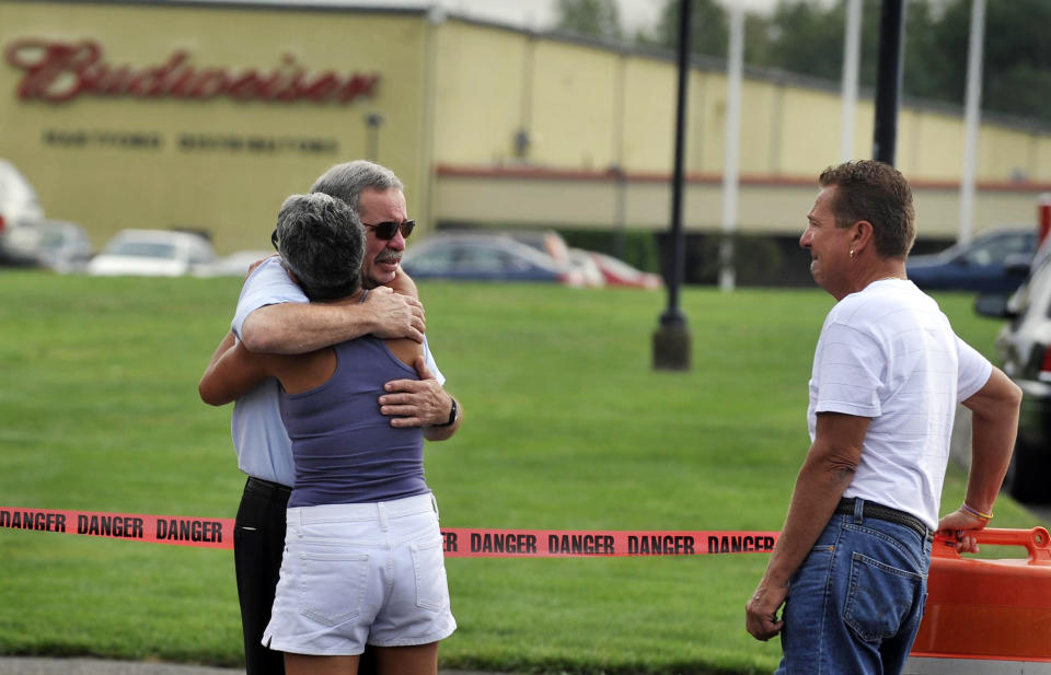 FILE - In this Aug. 4, 2010, file photo, employees and friends gather outside of Hartford Distributors after a mass shooting by an employee in Manchester, Conn. The gunman called 911 as police closed in and told the operator that he had experienced racism at the company and wished he’d killed even more co-workers. (AP Photo/Jessica Hill, File)