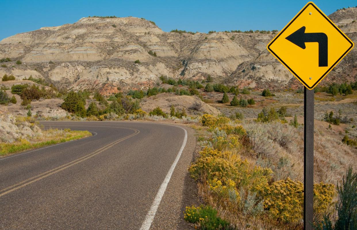 A road sign warns of a sharp left turn on a narrow road through Theodore Roosevelt National Park in southwest North Dakota.