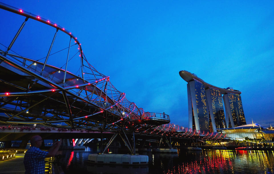 A man takes a photo next to the Helix Bridge, which connects to the Marina Bay Sands integrated resort. (Photo: REUTERS/Kevin Lam)