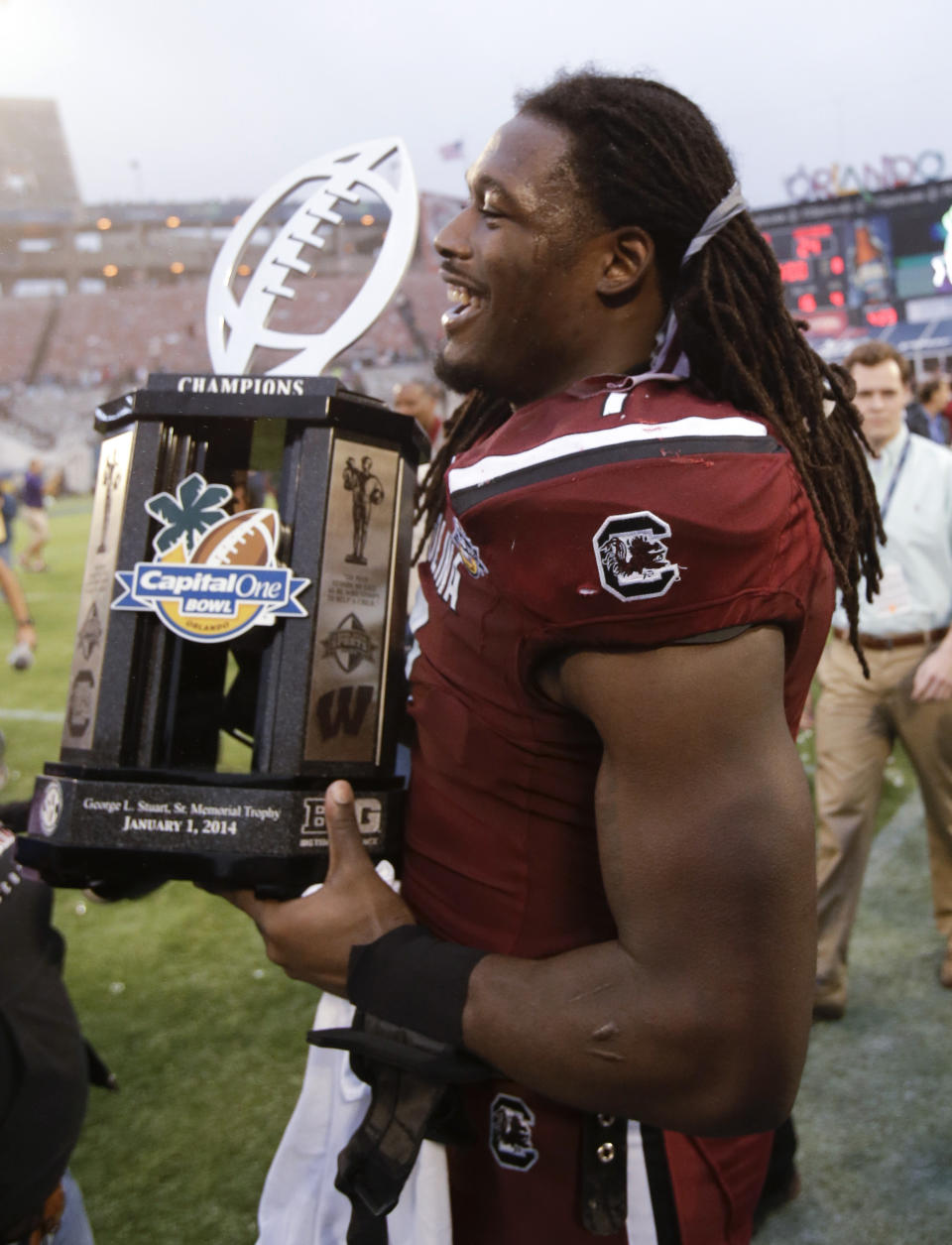 South Carolina defensive end Jadeveon Clowney walks around the field carrying the trophy after South Carolina defeated Wisconsin 34-24 the Capital One Bowl NCAA college football game in Orlando, Fla., Wednesday, Jan. 1, 2014. (AP Photo/John Raoux)