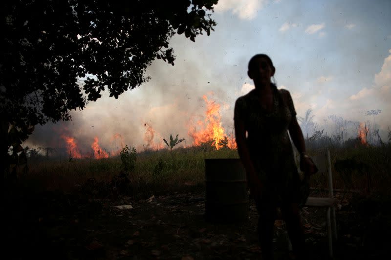 Miraceli de Oliveira reacts as the fire approaches her house in an area of Amazon rainforest, near Porto Velho