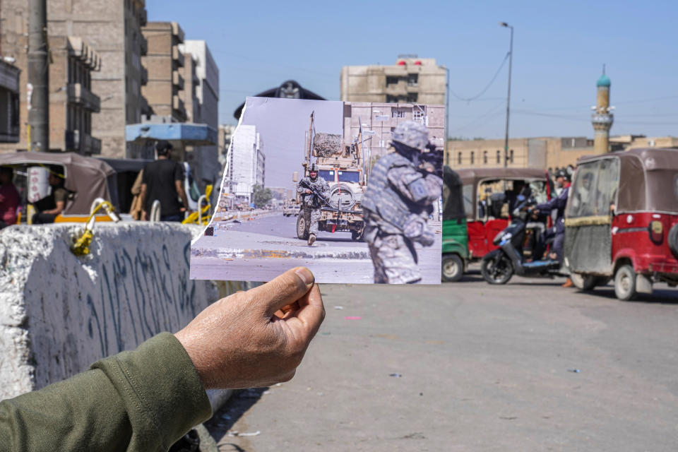 A photograph of U.S. troops taking positions during a gunfight with militants in the dominantly Sunni neighborhood of Fadhil in Baghdad, Iraq, Sunday, March 29, 2009, iis inserted into the scene at the same location on Friday, March 10, 2023, 20 years after the U.S. led invasion on Iraq and subsequent war. (AP Photo/Hadi Mizban)