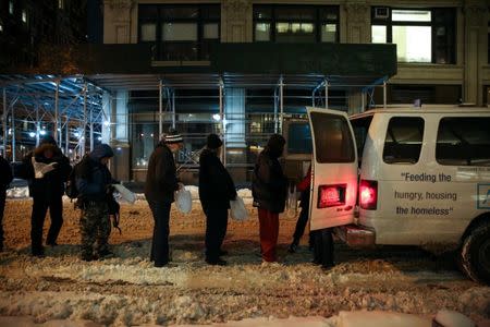 People stand in line as New York City's Coalition for the Homeless delivers food, donated clothing and supplies to homeless people as part of their weekly distribution during winter storm Grayson in Manhattan, New York City, U.S., January 4, 2018. REUTERS/Amr Alfiky