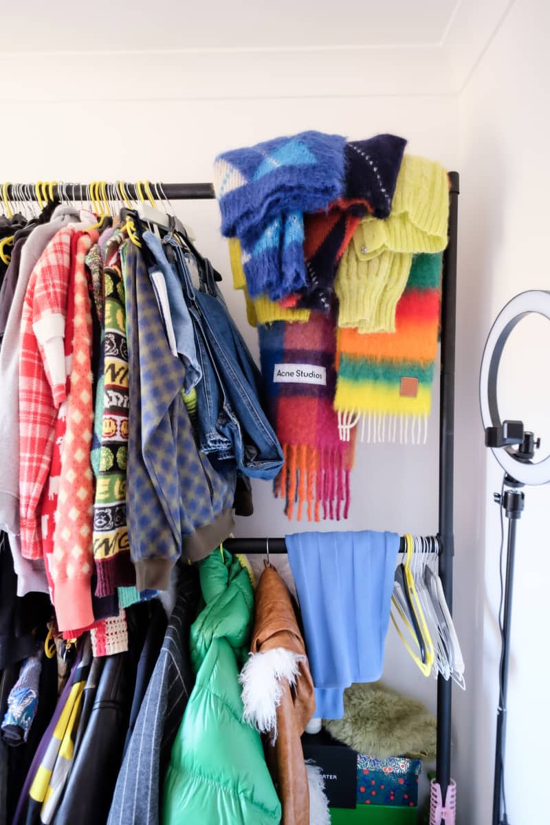 Clothing hangs from racks in corner of white room.