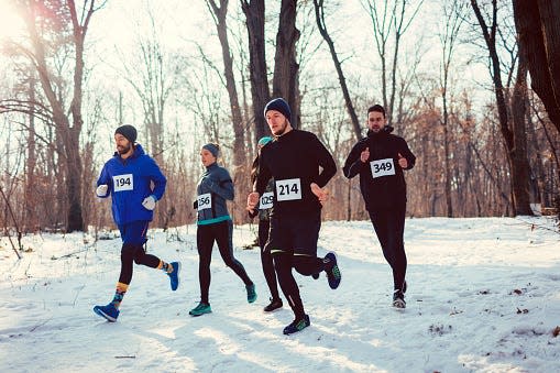 Marathon runners jogging during cold winter day in park