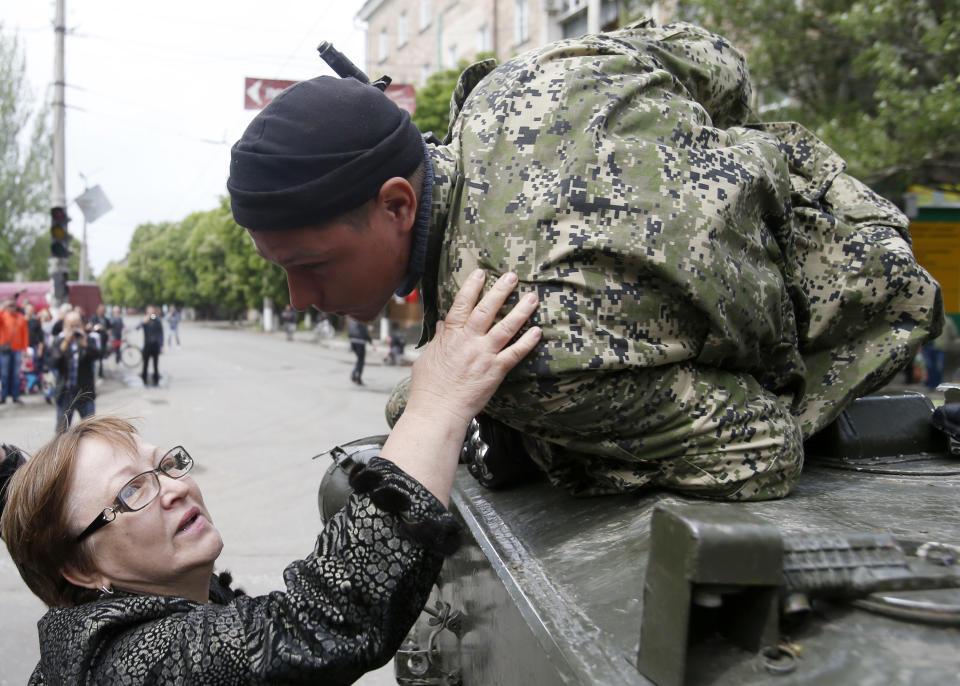 A woman welcomes a pro-Russian gunman atop an armored personal carrier during a Victory Day celebration, which commemorates the 1945 defeat of Nazi Germany, in the center of Slovyansk, eastern Ukraine, Friday, May 9, 2014. Putin's surprise call on Wednesday for delaying the referendum in eastern Ukraine appeared to reflect Russia's desire to distance itself from the separatists as it bargains with the West over a settlement to the Ukrainian crisis. But insurgents in the Russian-speaking east defied Putin's call and said they would go ahead with the referendum. (AP Photo/Darko Vojinovic)