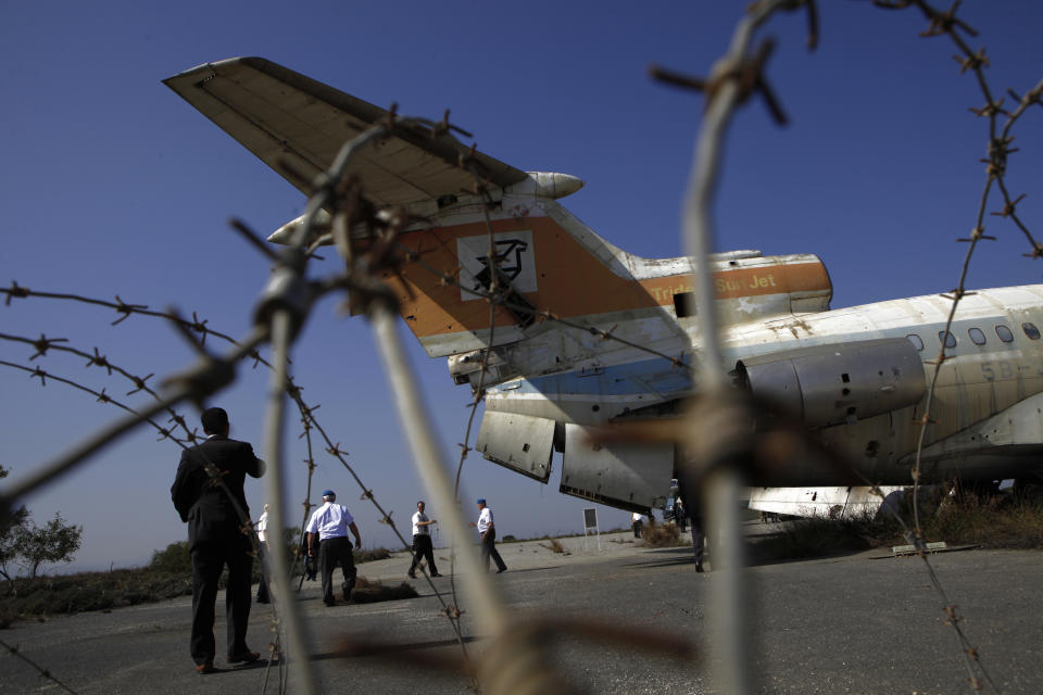 Canadian veteran soldiers who served with the United Nations Peacekeeping force on a war-divided Cyprus, look at an abandoned passenger aircraft, at the derelict Nicosia airport located inside the UN-controlled buffer zone on the capital's outskirts on Tuesday, March 18, 2014. A gutted Cyprus Airways Trident passenger jet a stone’s throw away from the terminal serves a reminder of the fierce battles that had raged there in July, 1974. Advancing Turkish forces had tried to seize the strategically important airport on the capital’s western outskirts, hours in to their invasion of Cyprus that was triggered by a coup aimed at uniting the island with Greece. Canadian soldiers then serving with the United Nations Peacekeeping force in Cyprus _ or UNFICYP _ helped repel the advance. Since then, it’s been the force’s headquarters midway through a 180 kilometer (112 mile) buffer zone that splits this ethnically divided island into a breakaway Turkish Cypriot north and a internationally recognized, Greek Cypriot south. Thousands of soldiers from 32 countries have donned the UN blue beret in Cyprus over half a century in what has become the longest serving peacekeeping force of its kind. Some 178 lost their lives here. (AP Photo/Petros Karadjias)