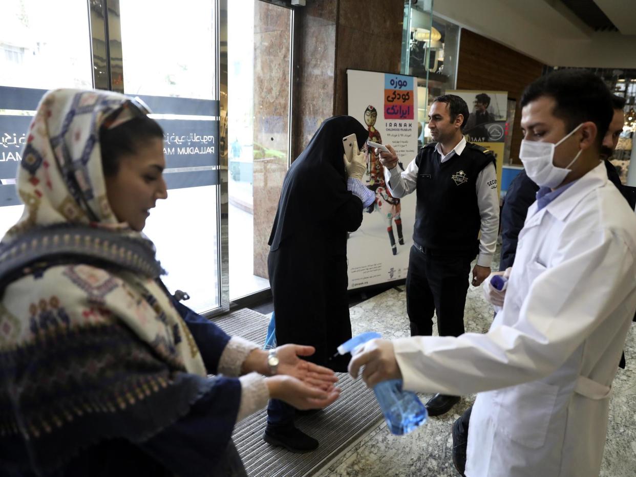 People have their temperature checked and their hands disinfected as they enter the Palladium Shopping Center, in northern Tehran, Iran: AP