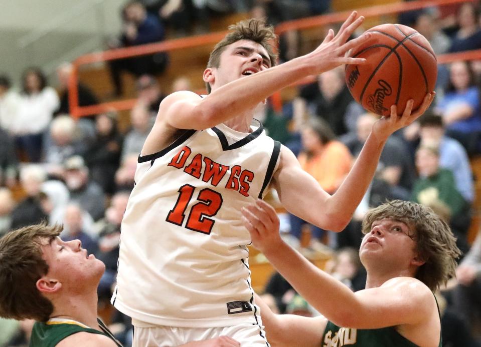 Tyler Dafoe goes up for a shot over two Sand Creek defenders during a 62-54 Bulldog victory Friday night.