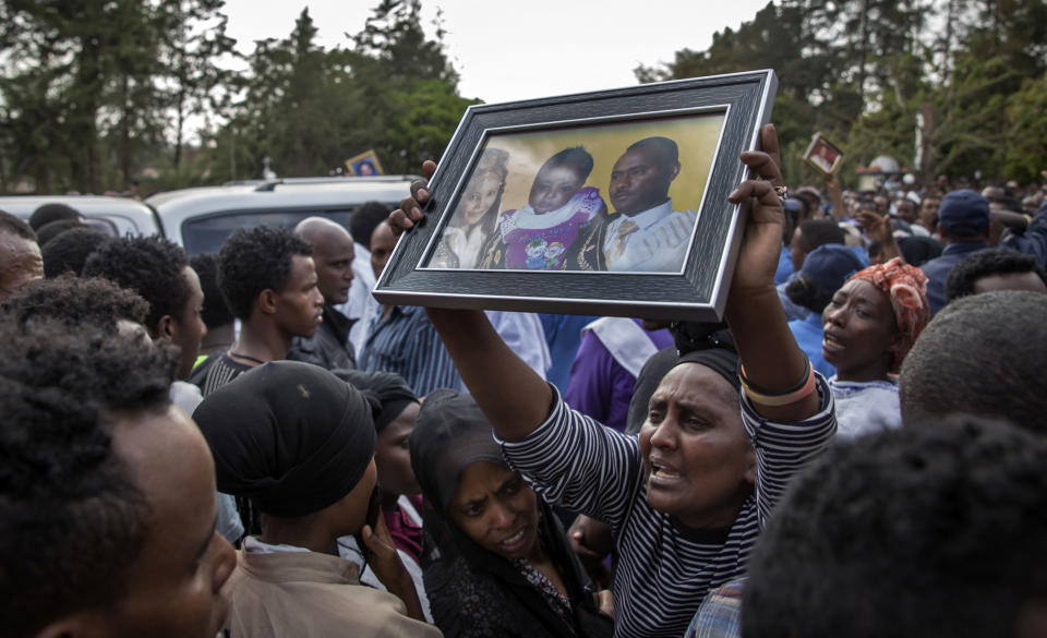 Relatives mourn as they lift portraits of family members they lost in the collapse of a mountain of trash at a garbage dump, during a funeral service held at the Gebrekristos church in Addis Ababa, Ethiopia Monday, March 13, 2017. The death toll reached more than 60 on Monday from the collapse at the dump on the outskirts of the capital, according to the state-affiliated Fana Broadcasting Corporate, as relatives waited for news of the dozens of people said to be missing. (AP Photo/Mulugeta Ayene)