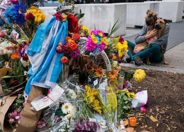 A woman hugs her dog after placing flowers she brought to a makeshift memorial that honors victims of an attack who were struck and killed by a rental truck driven by Sayfullo Saipov at Chambers and West Streets in New York, Nov. 4, 2017. (Craig Ruttle/AP, FILE)