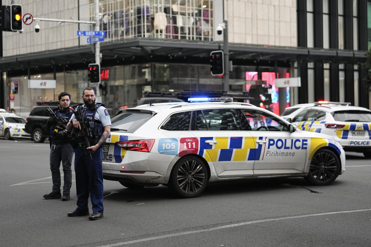 Armed New Zealand police officer stand at a road block in the central business district following a shooting in Auckland, New Zealand, Thursday, July 20, 2023. New Zealand police are responding to reports that a gunman has fired shots in a building in downtown Auckland. (AP Photo/Abbie Parr)