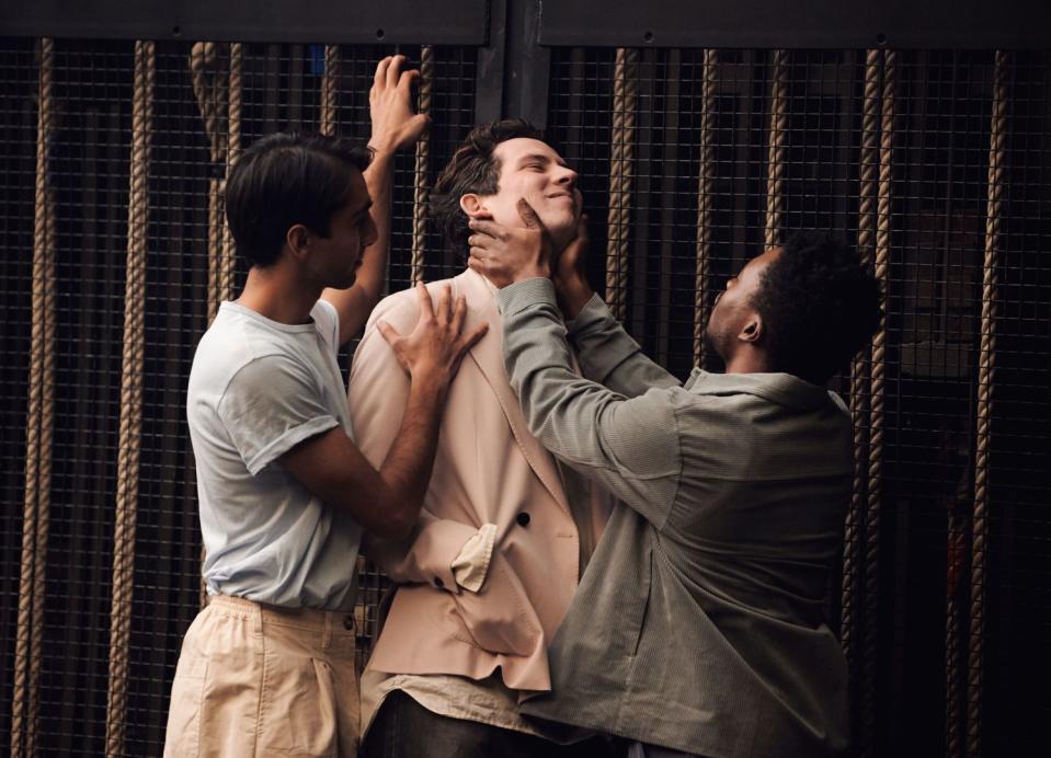 Two young Black men grab and hold a white man.