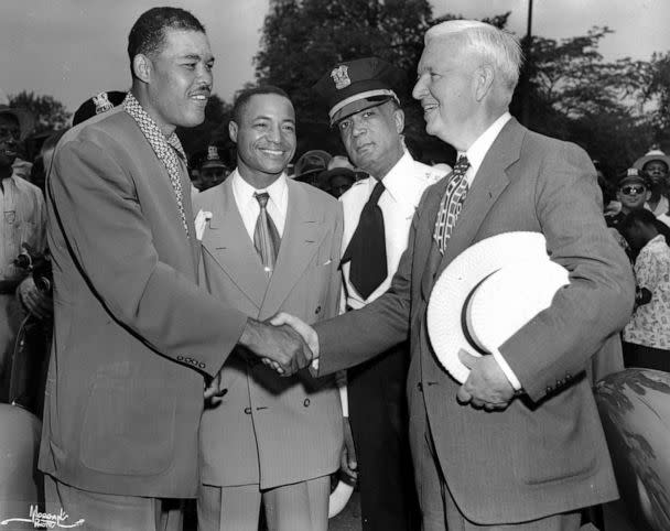 PHOTO: Former heavyweight boxer Joe Louis shakes hands with Chicago mayor Martin H. Kennelly at the Bud Billiken parade, sponsored by the Chicago Defender newspaper whose publisher, John H Sengstacke (second left) watches, in Chicago, in 1948.  (Robert Abbott Sengstacke/The Abbott Sengstacke Family Papers via Getty Images)