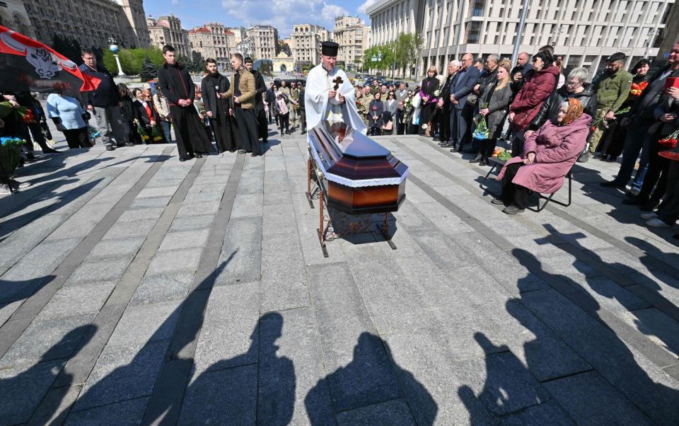 An Orthodox Priest carries out services at a coffin with the body of serviceman Yuri Moroz who died during combat with Russian troops, in Kyiv - SERGEI SUPINSKY/AFP