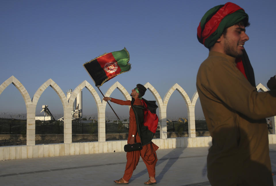 A man waves an Afghan flag during Independence Day celebrations in Kabul, Afghanistan, Monday, Aug. 19, 2019. Afghanistan's president is vowing to eliminate all safe havens of the Islamic State group as the country marks a subdued 100th Independence Day after a horrific wedding attack claimed by the local IS affiliate. (AP Photo/Rafiq Maqbool)