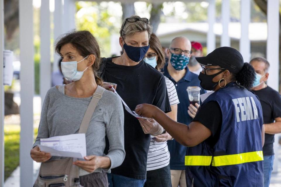 A FEMA employee assists Miami resident Heide Werthamer, 56, while she waits to receive a vaccine at the new FEMA-supported, state-run COVID-19 vaccine satellite site inside the Samuel K. Johnson Youth Center at Charles Hadley Park in Liberty City, Florida, on Friday, March, 19, 2021.