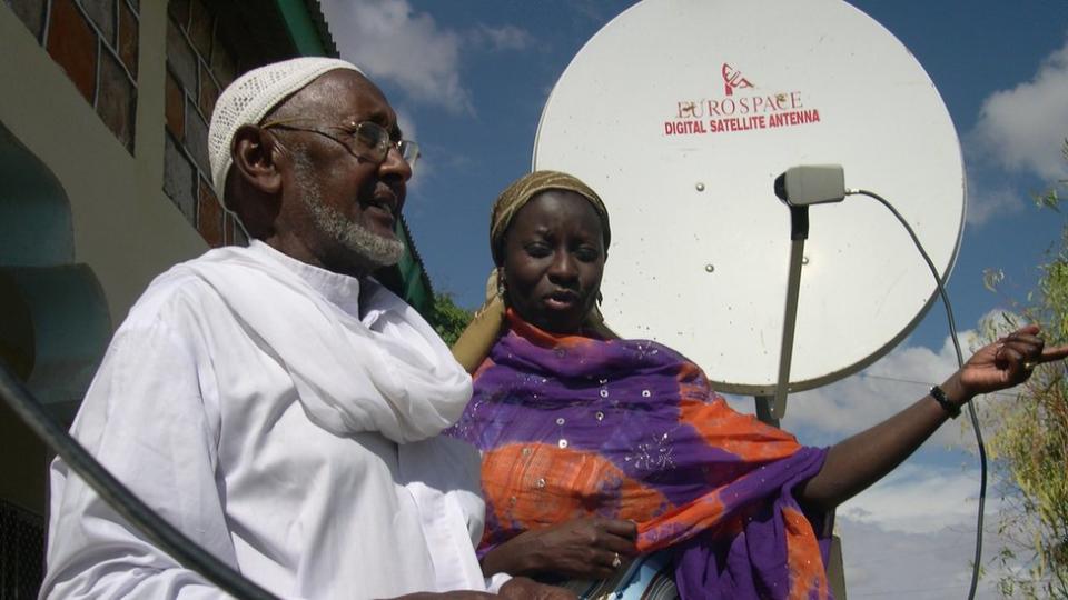 A man and a woman in Somaliland stand in front of a satellite dish.