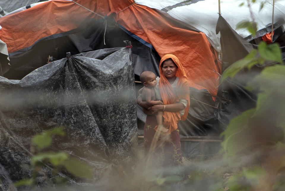 FILE - In this June 29, 2018, file photo, Rohingya refugees look out from their camp near a fence during a government-organized media tour to a no-man's land between Myanmar and Bangladesh, near Taungpyolatyar village, Maung Daw, northern Rakhine State, Myanmar. The U.N. Human Rights Council said in a statement on Tuesday, May 14, 2019 that there has been no progress in the crisis over Myanmar’s mostly Muslim Rohingya minority, more than 1 million of whom have fled military “clearance operations” in the northwest Rakhine region. It said those remaining in the country live in displacement camps and in fear. (AP Photo/Min Kyi Thein, File)