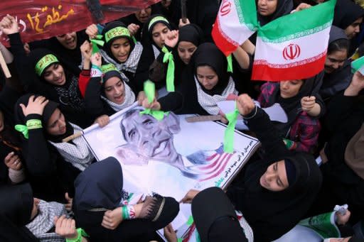 Iranian women hold a banner bearing a cartoon of US President Barack Obama, outside the former US embassy in Tehran. Thousands of Iranians chanting "Death to America" rallied to mark the 33rd anniversary of the seizure of the US embassy in Tehran