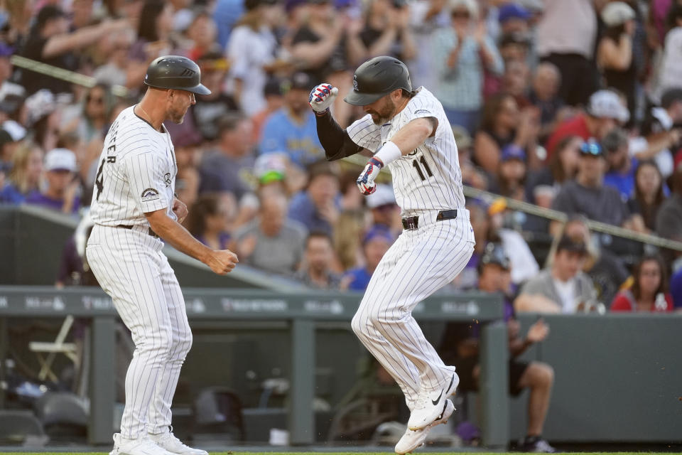 Colorado Rockies third base coach Warren Schaeffer, left, congratulates Jake Cave, right, who circles the bases after hitting a solo home run off Milwaukee Brewers starting pitcher Tobias Myers in the sixth inning of a baseball game Thursday, July 4, 2024, in Denver. (AP Photo/David Zalubowski)