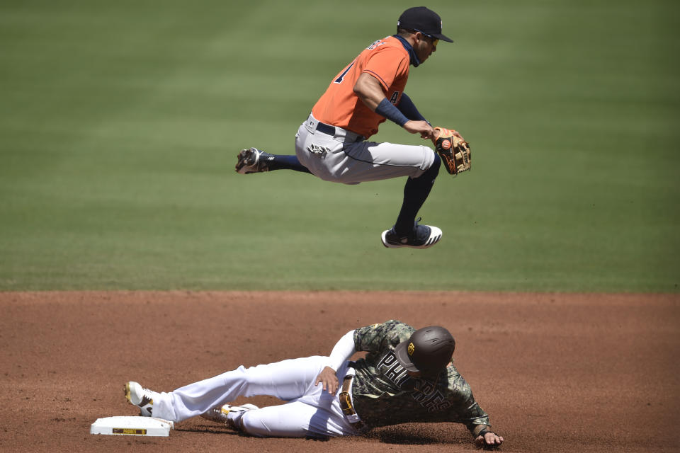 Houston Astros shortstop Carlos Correa, top, jumps to avoid San Diego Padres' Manny Machado as Machado steals second base off an errant throw during the first inning of a baseball game in San Diego, Sunday, Aug. 23, 2020. (AP Photo/Kelvin Kuo)