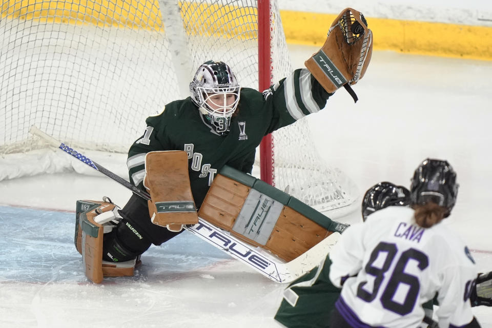 Boston goalie Aerin Frankel, left, grabs the puck for a save in front of Minnesota forward Michela Cava, right, during the third period of Game 1 of a PWHL hockey championship series, Sunday, May 19, 2024, in Lowell, Mass. (AP Photo/Steven Senne)
