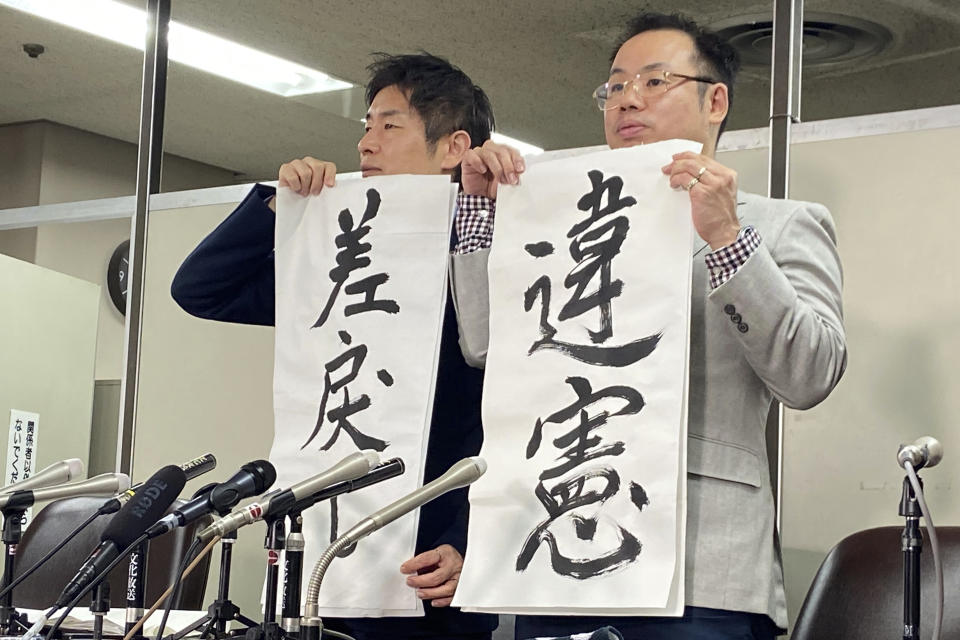 Lawyers of a claimant, Kazuyuki Minami, left, and Masafumi Yoshida, right, holds signs that read "Unconstitutional", right, and "Back (to High Court)" during a press conference following the ruling of the Supreme Court Wednesday, Oct. 25, 2023, in Tokyo. Japan’s Supreme Court on Wednesday ruled that a law requiring transgender people to have sterilization surgery in order to officially change their gender is unconstitutional. The claimant is only identified as a resident in western Japan. (AP Photo/Mari Yamaguchi)