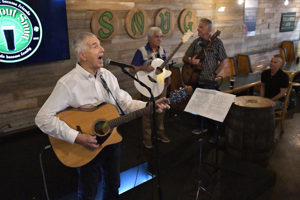 Jay Birmingham, from left, opens the show as Bob Fernee and Rodney Smith wait to join him on stage to perform at The Stout Snug in Murray Hill Wednesday evening. Birmingham, Fernee and Smith make up the local band Cerberus. The trio, now in their 70s, were also among the founders of the River Run in 1978. They will be performing along the route of this year's Gate River Run for the participants as they run past Saturday morning.